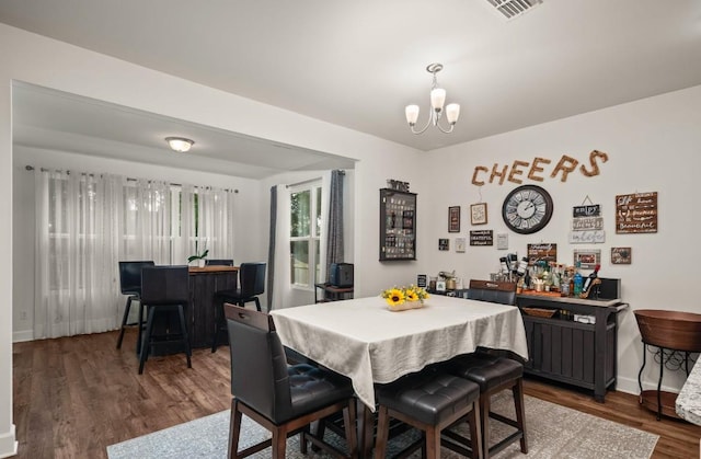 dining space featuring indoor bar, dark hardwood / wood-style floors, and a notable chandelier