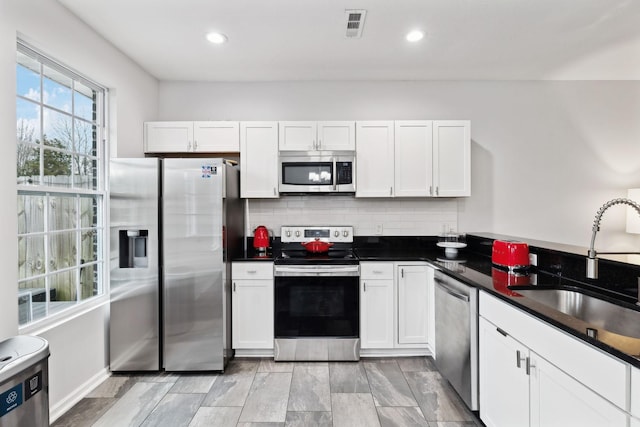 kitchen featuring tasteful backsplash, stainless steel appliances, sink, and white cabinets