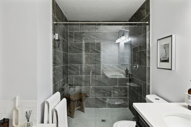 bathroom with vanity, a textured ceiling, toilet, and tiled shower