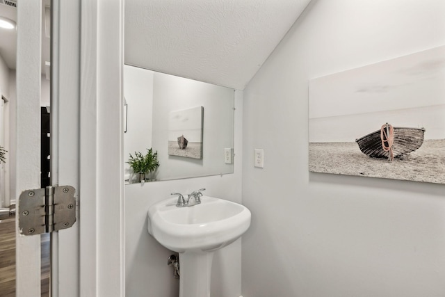 bathroom featuring lofted ceiling and a textured ceiling