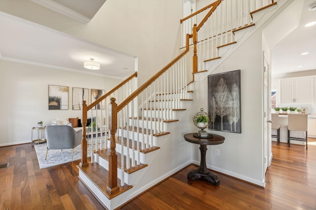 stairway with hardwood / wood-style flooring, crown molding, and a towering ceiling