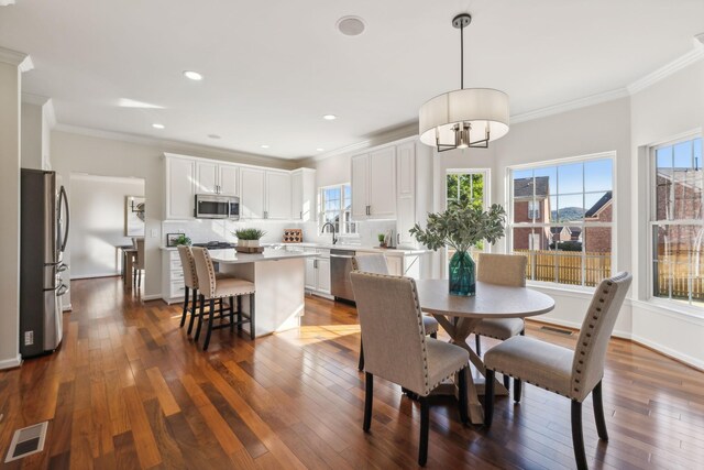 dining room featuring sink, crown molding, and dark wood-type flooring