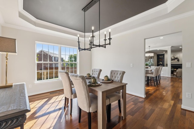 dining space featuring dark hardwood / wood-style flooring, a tray ceiling, and crown molding