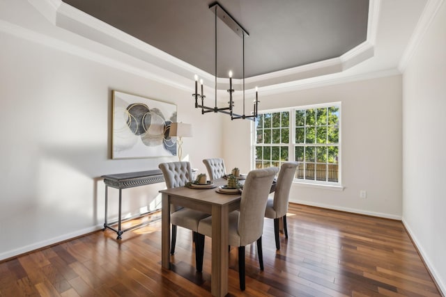 dining room featuring dark hardwood / wood-style floors, a notable chandelier, a tray ceiling, and crown molding