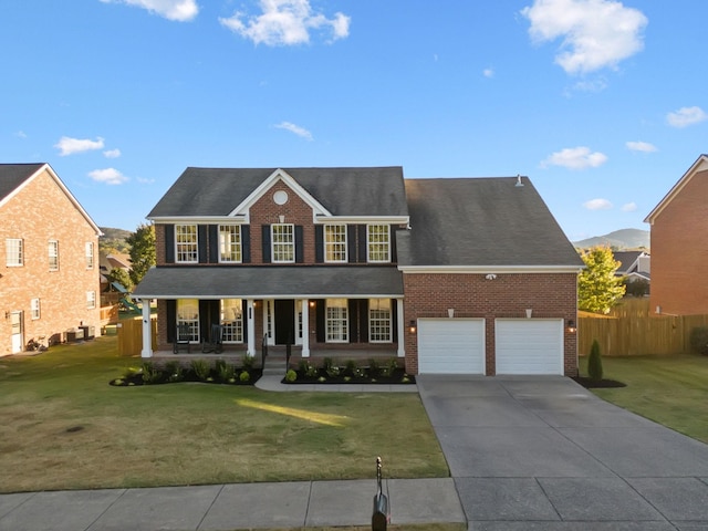 colonial-style house featuring a porch, a garage, and a front yard