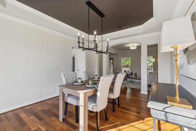 dining space featuring a raised ceiling, wood-type flooring, and crown molding