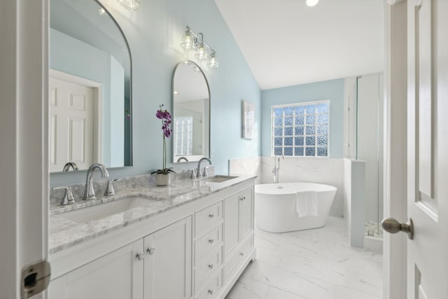 bathroom featuring vanity, a bath, and tile walls