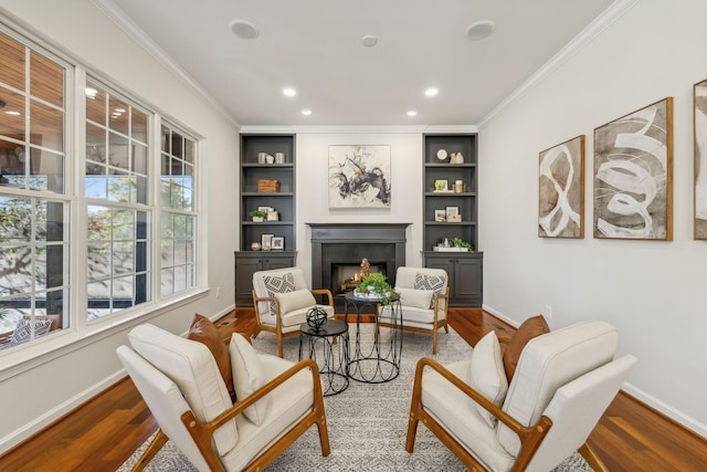 living area featuring crown molding, hardwood / wood-style floors, and built in features