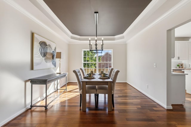 dining area featuring dark hardwood / wood-style floors, ornamental molding, a tray ceiling, and a notable chandelier