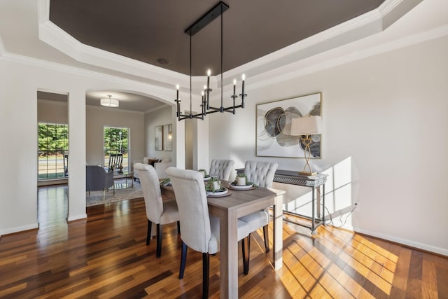 dining space with dark wood-type flooring, a tray ceiling, and crown molding