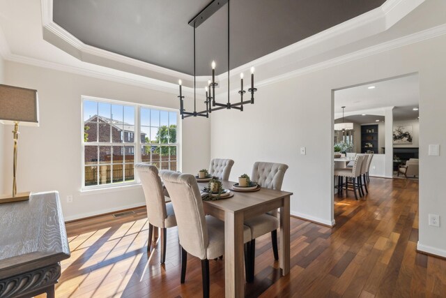 dining room featuring dark wood-type flooring, crown molding, and a raised ceiling