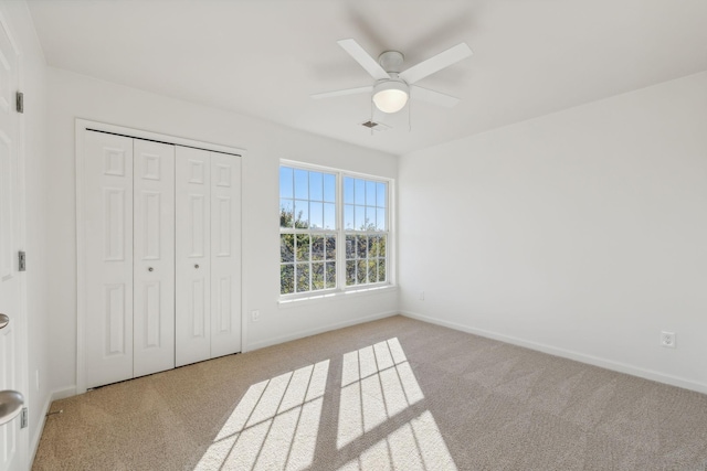 unfurnished bedroom featuring ceiling fan, a closet, and light carpet