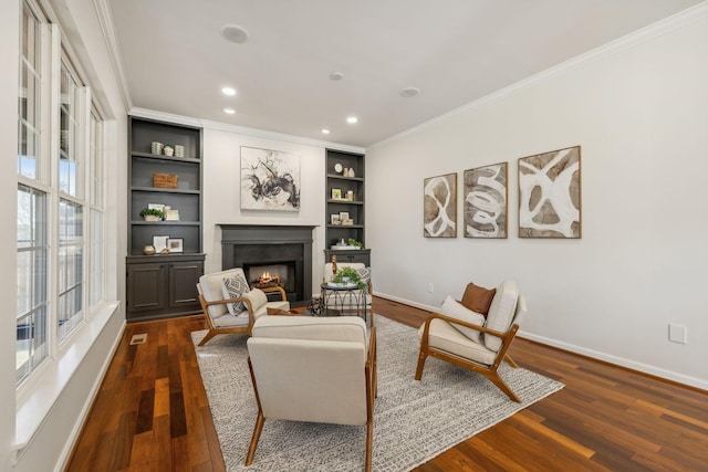 sitting room with crown molding, built in features, and dark hardwood / wood-style flooring