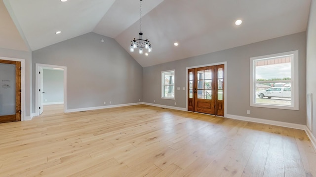 unfurnished living room with an inviting chandelier, high vaulted ceiling, and light wood-type flooring