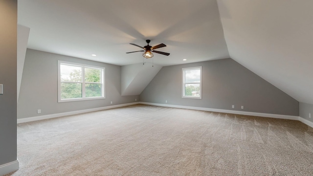 additional living space with lofted ceiling, ceiling fan, light colored carpet, and a healthy amount of sunlight