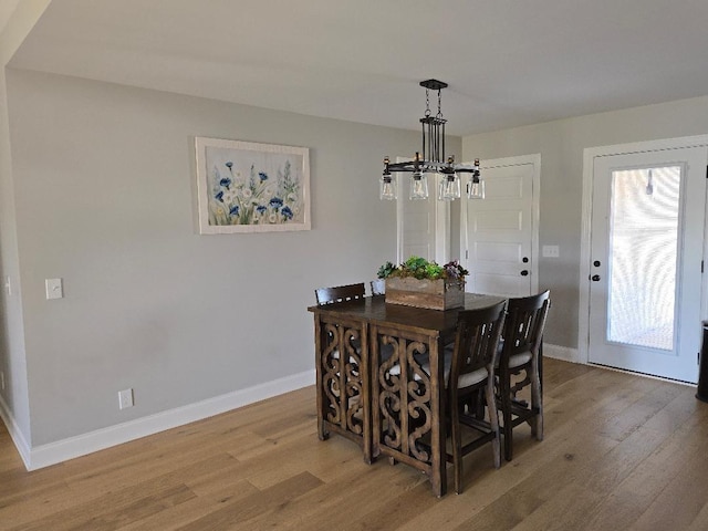 dining space featuring a notable chandelier, light wood-type flooring, and baseboards