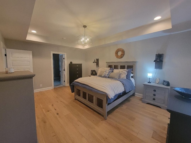 bedroom with baseboards, a tray ceiling, recessed lighting, and light wood-style floors