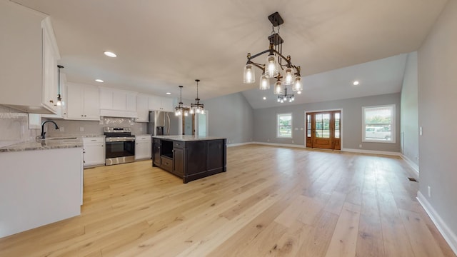 kitchen featuring stainless steel appliances, a kitchen island, sink, and white cabinets