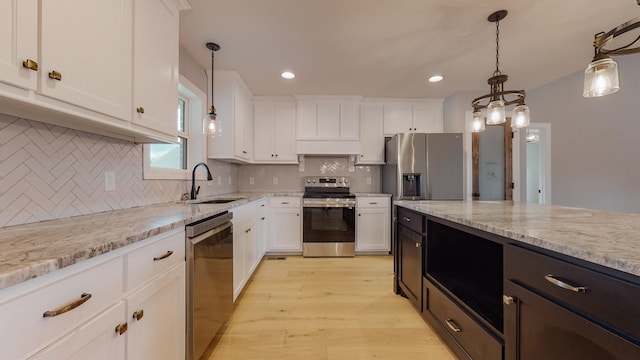 kitchen with white cabinetry, sink, pendant lighting, and stainless steel appliances