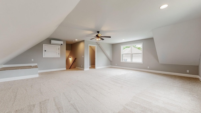 additional living space featuring lofted ceiling, ceiling fan, light colored carpet, and a wall mounted AC