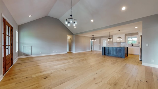 kitchen with lofted ceiling, an inviting chandelier, decorative light fixtures, light hardwood / wood-style flooring, and a kitchen island