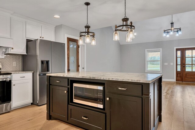 kitchen with appliances with stainless steel finishes, light wood-type flooring, backsplash, and white cabinetry