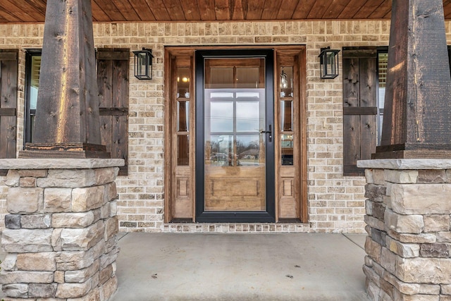 property entrance with a porch and brick siding