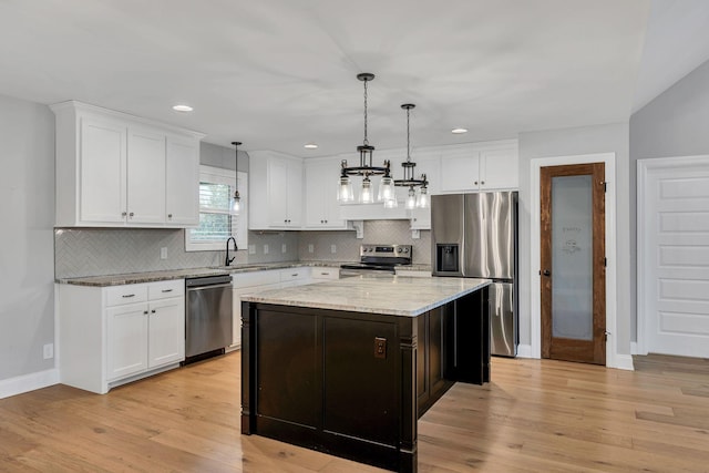 kitchen featuring light wood-style floors, appliances with stainless steel finishes, white cabinets, and a sink