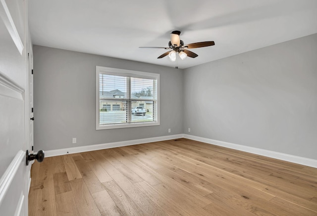 empty room featuring ceiling fan, light wood-type flooring, and baseboards