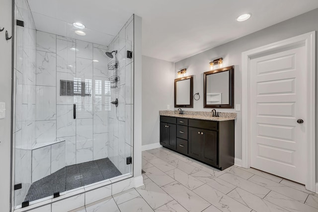 bathroom featuring a stall shower, marble finish floor, a sink, and double vanity