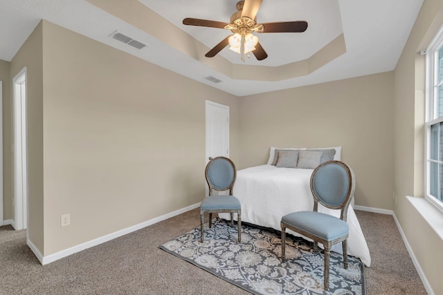 bedroom with a raised ceiling, carpet floors, and ceiling fan