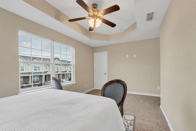 carpeted bedroom featuring ceiling fan and a tray ceiling