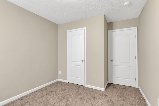 unfurnished bedroom with light colored carpet and a textured ceiling