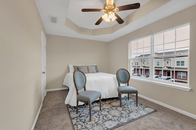 carpeted bedroom featuring ceiling fan and a tray ceiling