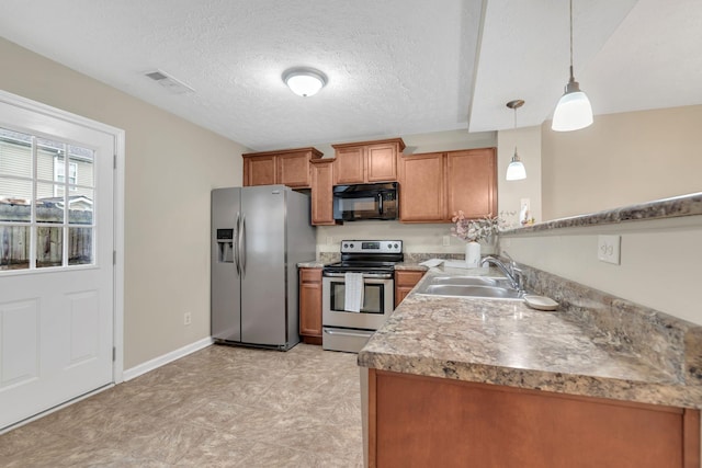 kitchen featuring hanging light fixtures, sink, a textured ceiling, and appliances with stainless steel finishes