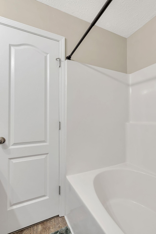 bathroom with shower / tub combination and a textured ceiling