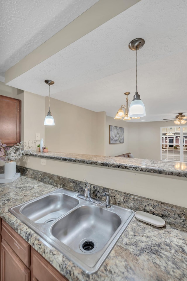 kitchen featuring decorative light fixtures, sink, and a textured ceiling