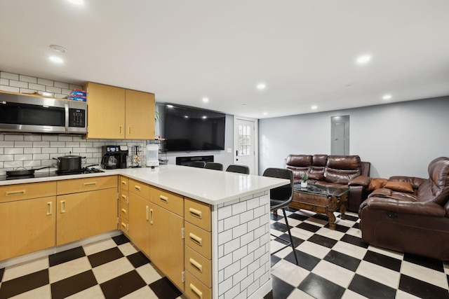 kitchen with backsplash, kitchen peninsula, light brown cabinets, and black cooktop