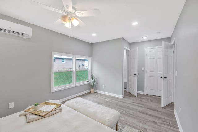 bedroom featuring a wall mounted air conditioner, light hardwood / wood-style floors, and ceiling fan