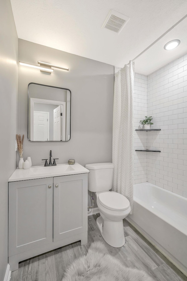 full bathroom featuring vanity, wood-type flooring, shower / tub combo with curtain, and toilet