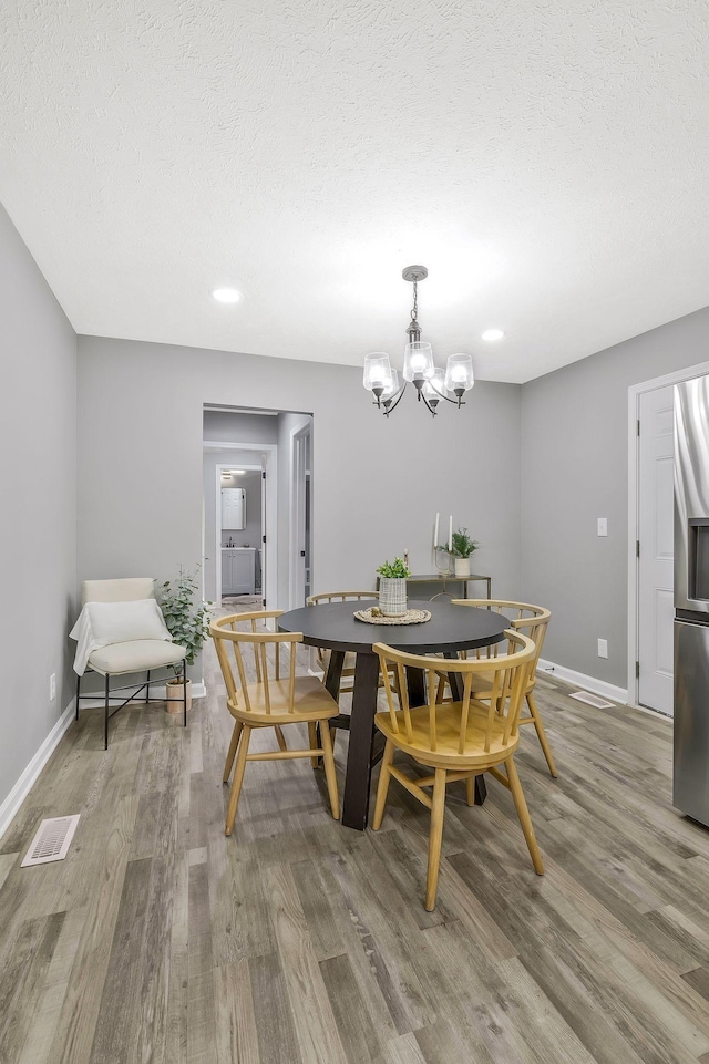 dining area featuring hardwood / wood-style flooring, a textured ceiling, and a chandelier