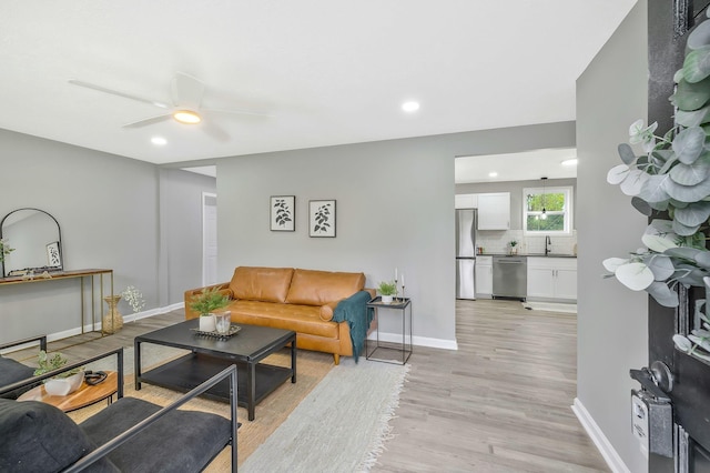 living room with ceiling fan, sink, and light wood-type flooring