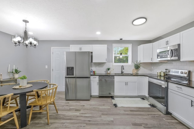 kitchen featuring appliances with stainless steel finishes, sink, hanging light fixtures, and white cabinets