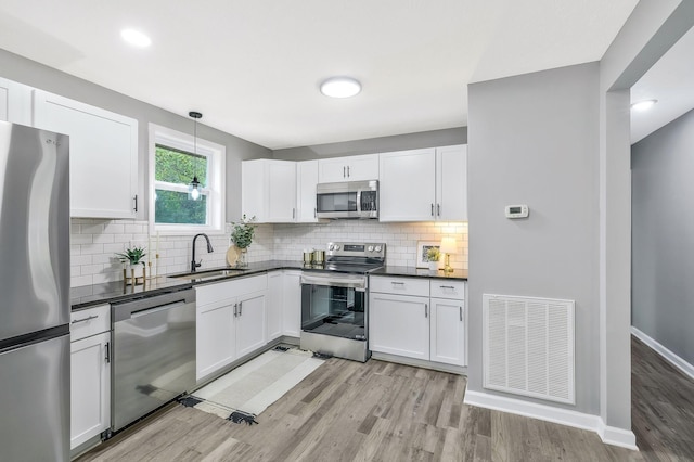 kitchen with white cabinetry, sink, hanging light fixtures, and appliances with stainless steel finishes