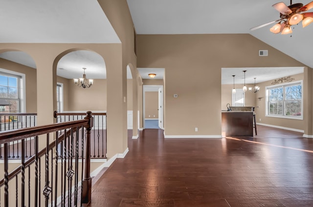 unfurnished living room featuring dark hardwood / wood-style flooring, sink, ceiling fan with notable chandelier, and vaulted ceiling