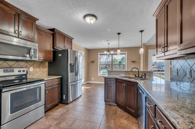 kitchen featuring light tile patterned flooring, sink, hanging light fixtures, stainless steel appliances, and light stone countertops