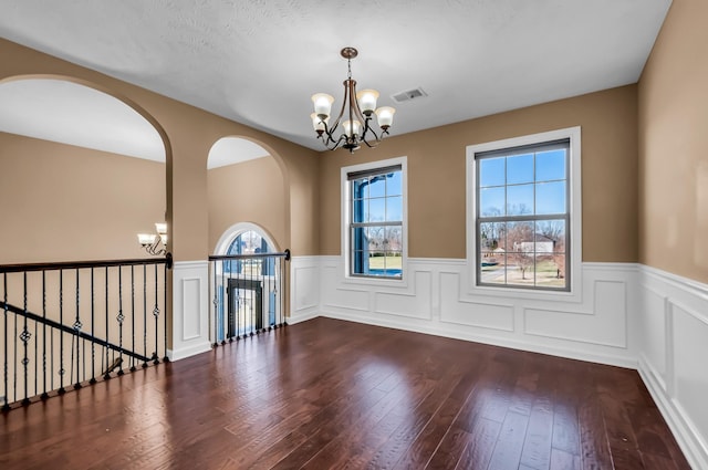 empty room featuring an inviting chandelier and hardwood / wood-style flooring