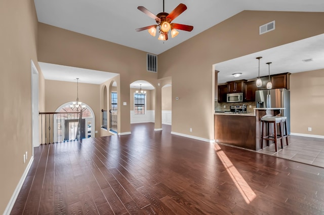 unfurnished living room with dark wood-type flooring, high vaulted ceiling, and ceiling fan with notable chandelier