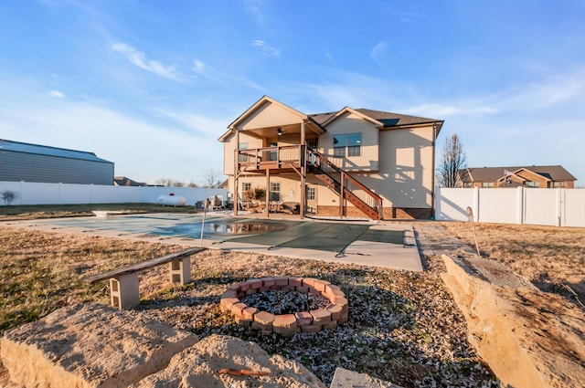 rear view of house with a fire pit, a patio area, and a covered pool