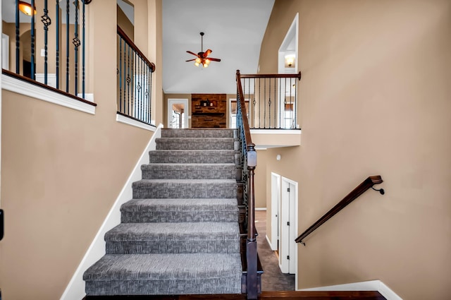 stairs featuring ceiling fan and a high ceiling